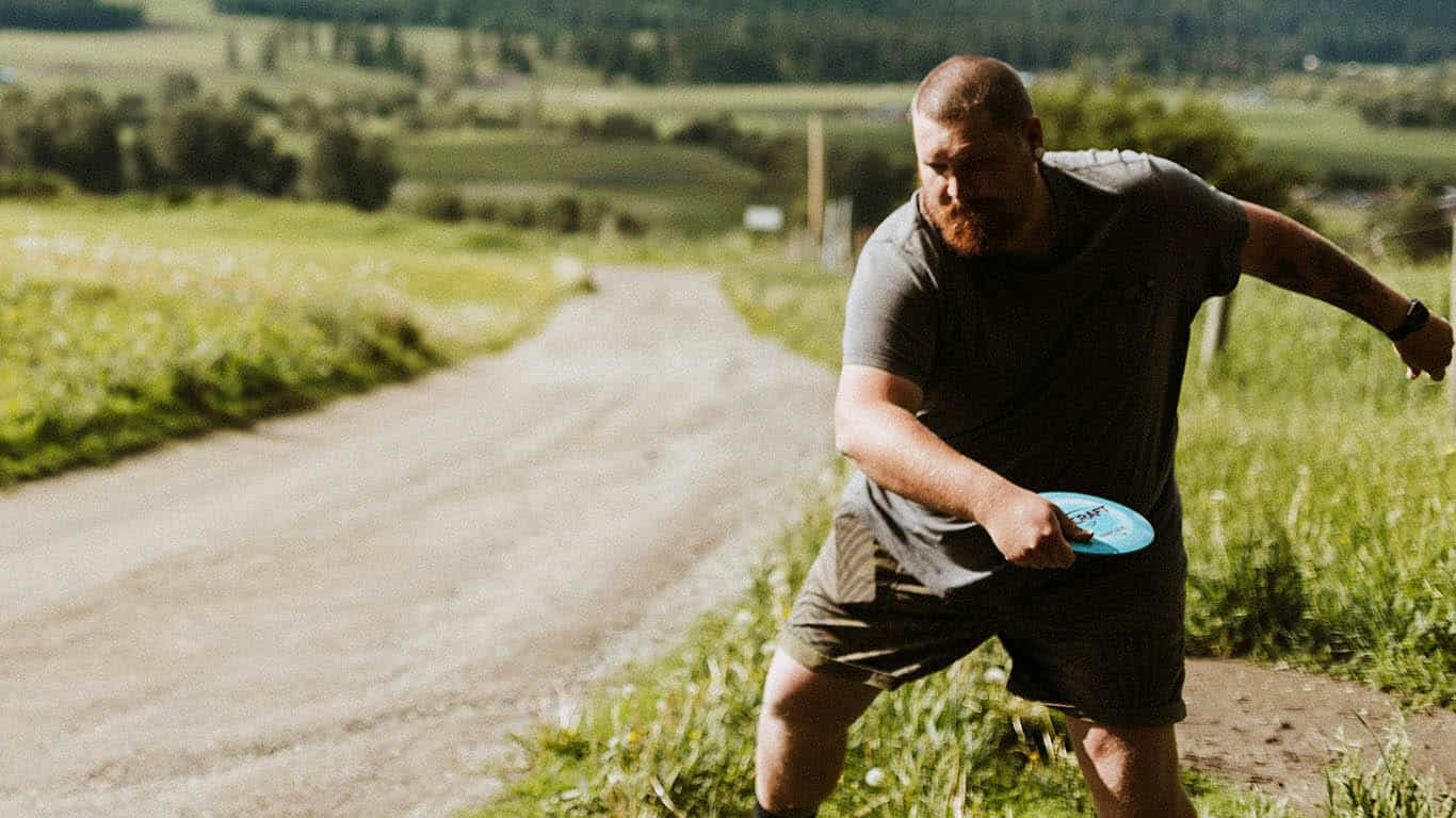 A man getting ready to throw a disc with backhand throw A man getting ready to throw a disc with backhand throw