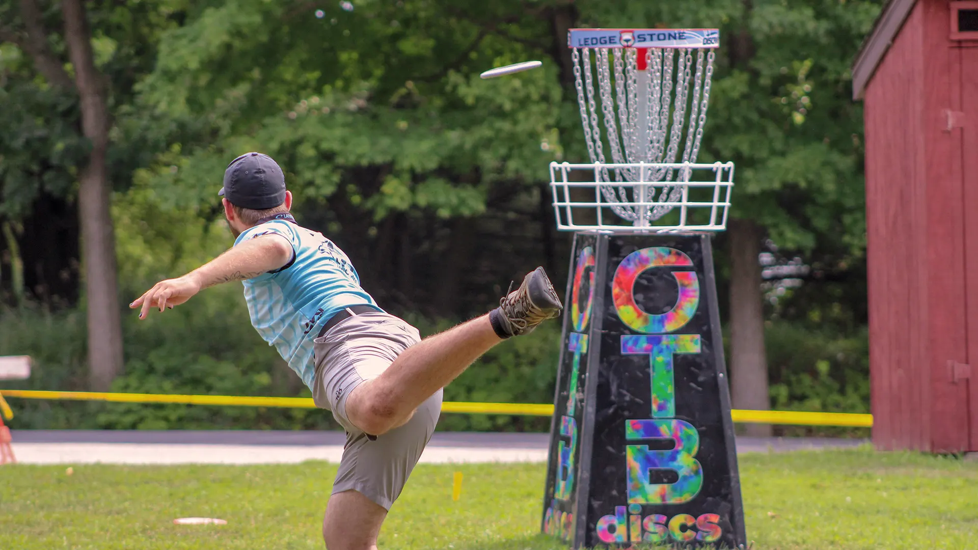 a disc golf player throwing a disc into a basket at OTB championship